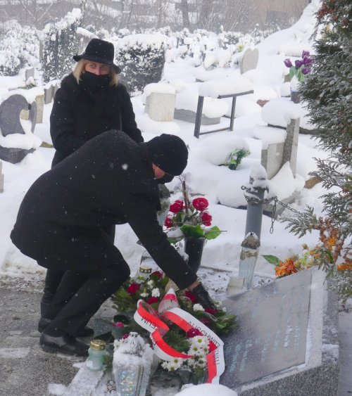 Zdjęcie przedstawia osoby składające kwiaty na mogile ofiar Marszu śmierci