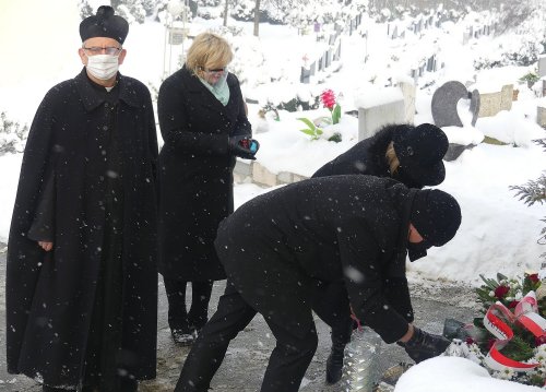 Zdjęcie przedstawia osoby składające kwiaty na mogile ofiar Marszu śmierci