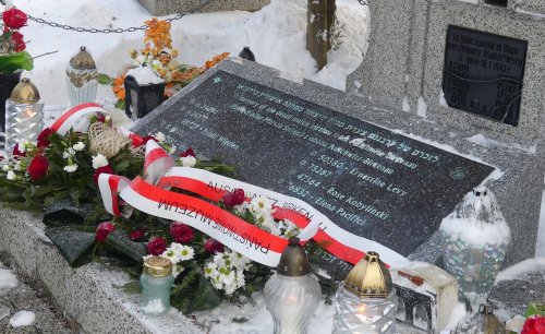Zdjęcie przedstawia osoby składające kwiaty na mogile ofiar Marszu śmierci